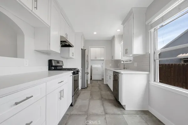 a kitchen with white cabinets appliances and sink