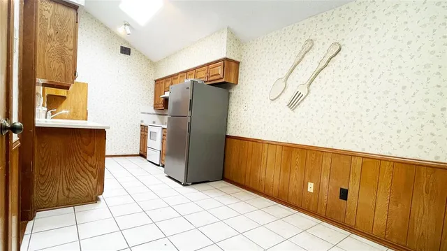 a view of a refrigerator in kitchen and a window