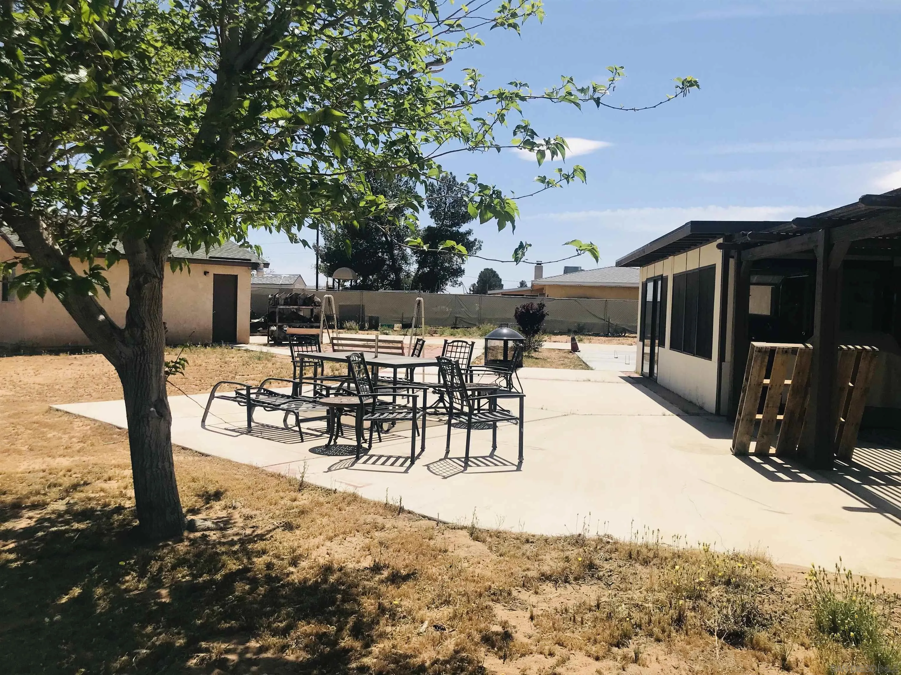 14665 Hopi Road Apple Valley, CA 92307 - Photo 7 of 21 a view of a patio with table and chairs potted plants and large tree
