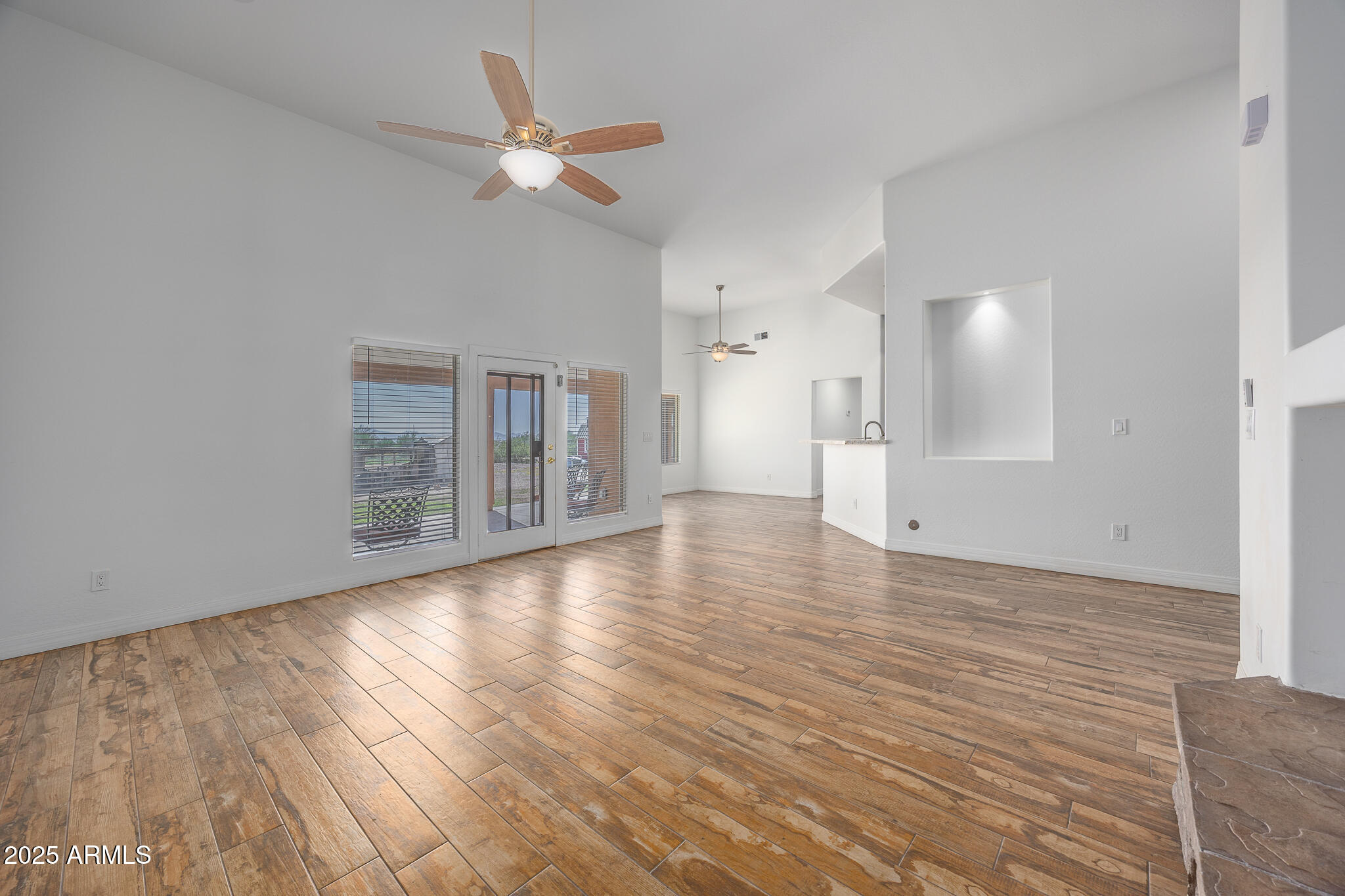 30826 North Crozier Road Wittmann, AZ 85361 - Photo 15 of 65 an empty room with wooden floor fan and windows