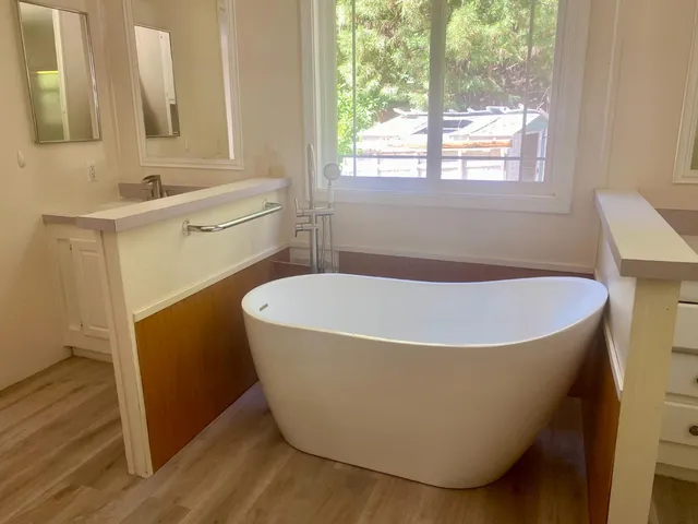 a white bath tub sitting in a bathroom next to a window