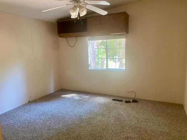 an empty room with a chandelier fan and windows
