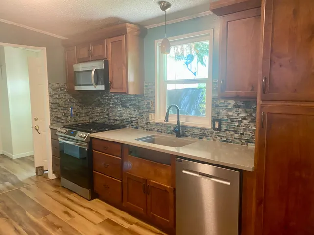 a kitchen with stainless steel appliances granite countertop a sink stove and refrigerator
