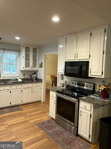 a kitchen with granite countertop a stove a sink and a microwave
