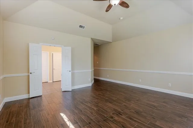 an empty room with wooden floor fan and windows