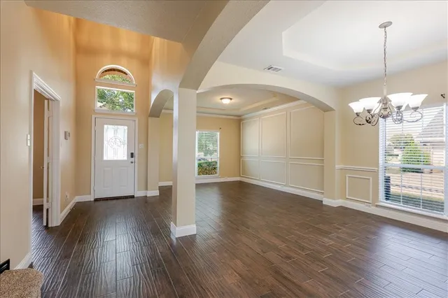 an empty room with wooden floor mirror and windows