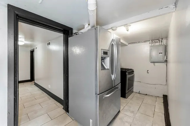 a view of a refrigerator in kitchen and an empty room