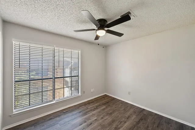 an empty room with wooden floor fan and windows