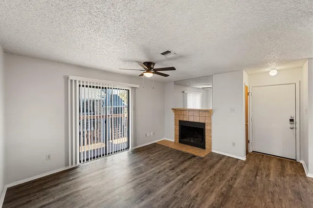 a view of an empty room with wooden floor fireplace and a window