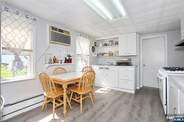 a kitchen with a stove a sink dishwasher a dining table and chairs with wooden floor