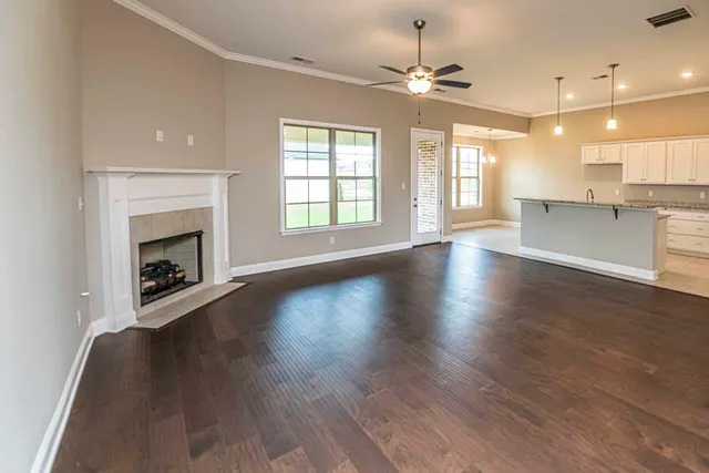 an empty room with wooden floor fireplace and windows