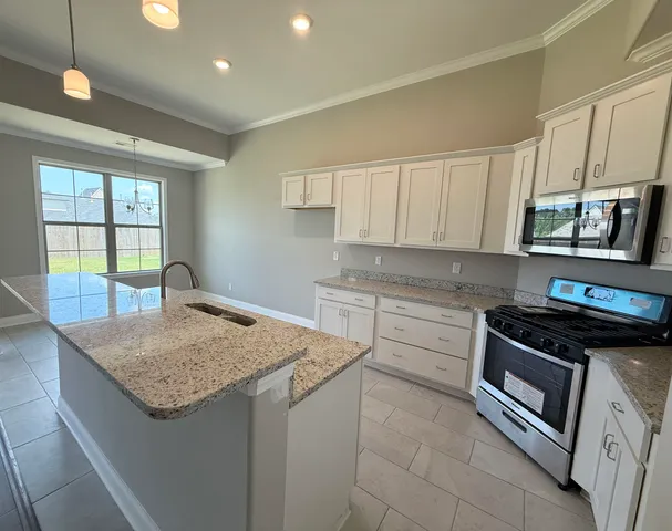 a kitchen with granite countertop a sink stainless steel appliances and white cabinets