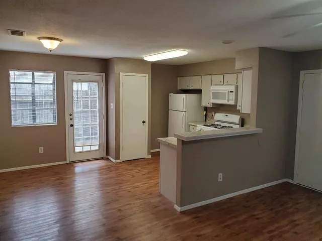a kitchen with kitchen island wooden floors appliances and cabinets