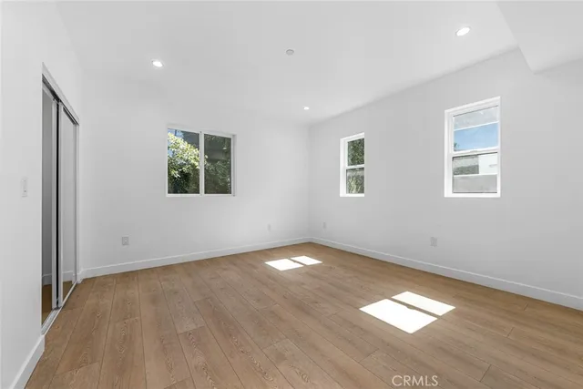 an empty room with wooden floor and windows