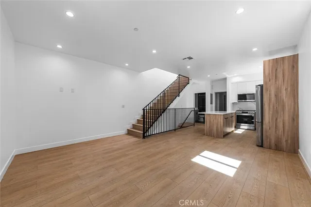 a view of a livingroom with wooden floor and stairs