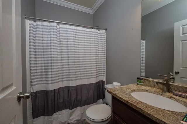 a bathroom with a granite countertop toilet sink and mirror