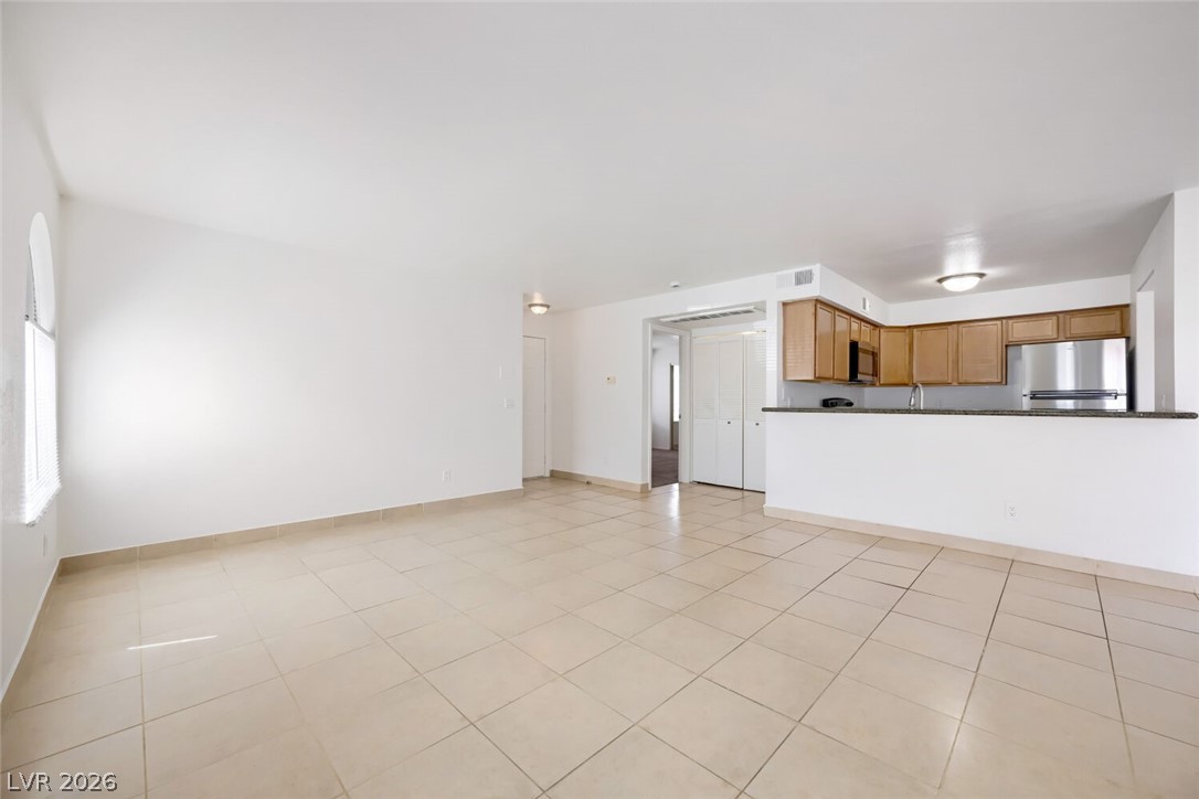 9325 West Desert Inn Road, Unit 177 Las Vegas, NV 89117 - Photo 4 of 24 An open concept living area features resilient tile flooring connecting to a modern kitchen.