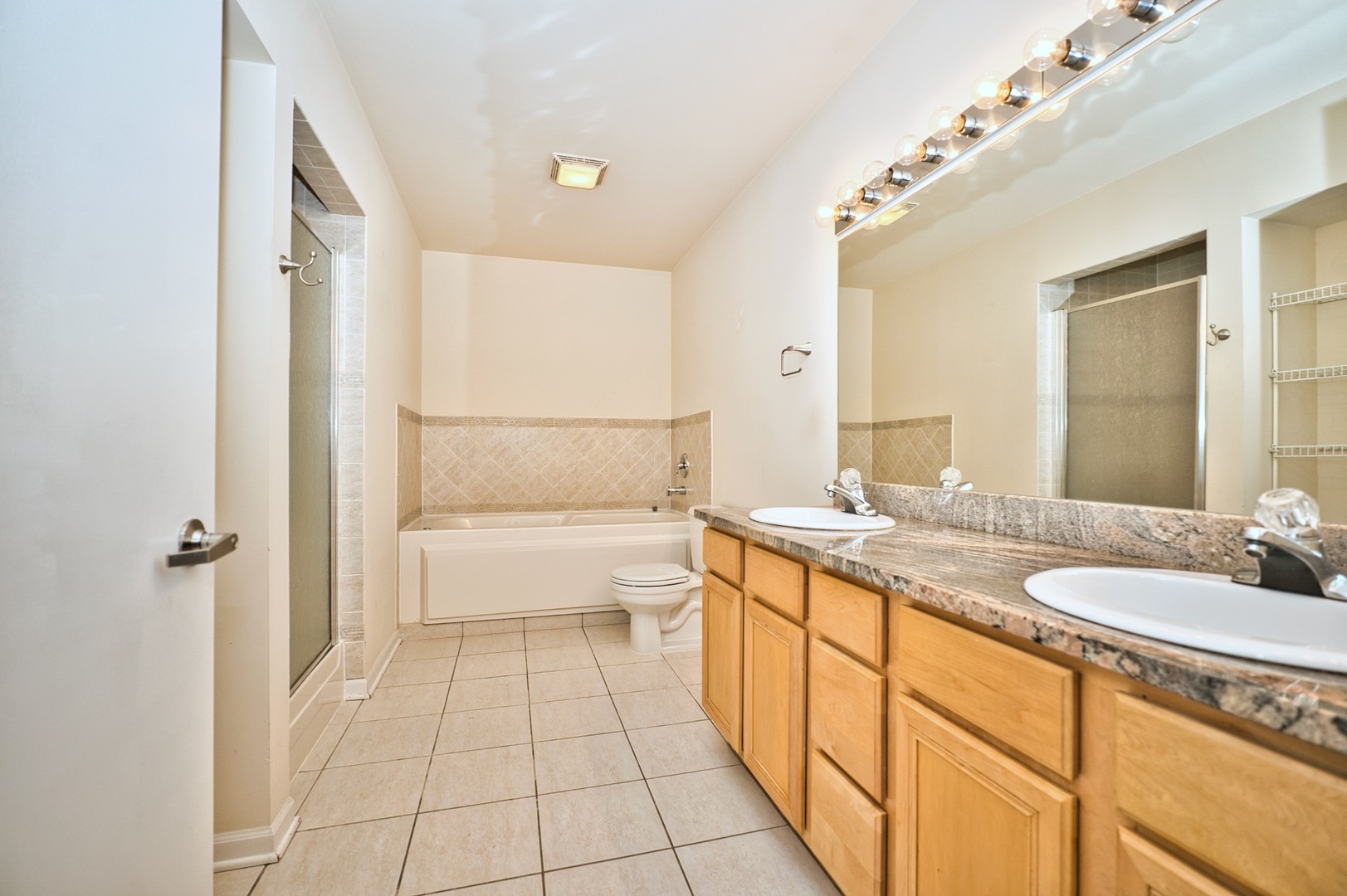 2317 West Wolfram Street, Unit 515 Chicago, IL 60618 - Photo 23 of 35 a bathroom with a granite countertop sink a mirror and a bathtub