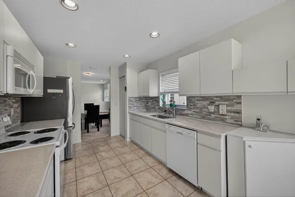 a kitchen with kitchen island granite countertop a sink white cabinets and stainless steel appliances