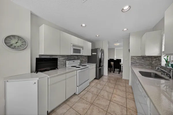 a white kitchen with a stove a microwave and a refrigerator