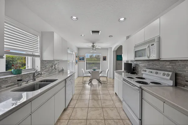 a large white kitchen with stainless steel appliances granite countertop a sink and cabinets