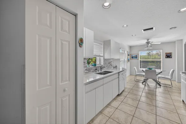 a large white kitchen with cabinets and chairs