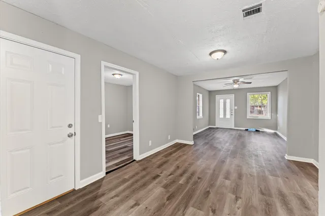 an empty room with wooden floor closet and windows