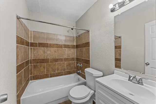 a bathroom with a bathtub shower sink mirror vanity and toilet