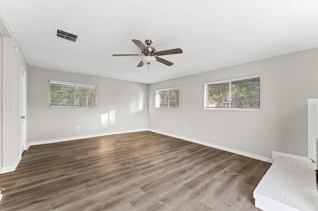 a view of empty room with wooden floor and fan