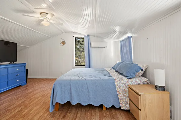 a bedroom with a bed and a flat tv screen on dresser