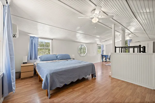 a large bedroom with a bed and a large window with wooden floor