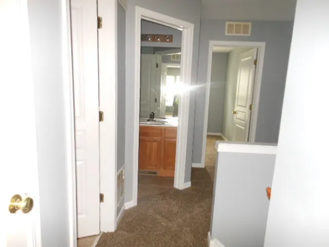 a view of a hallway with bathroom and mirror