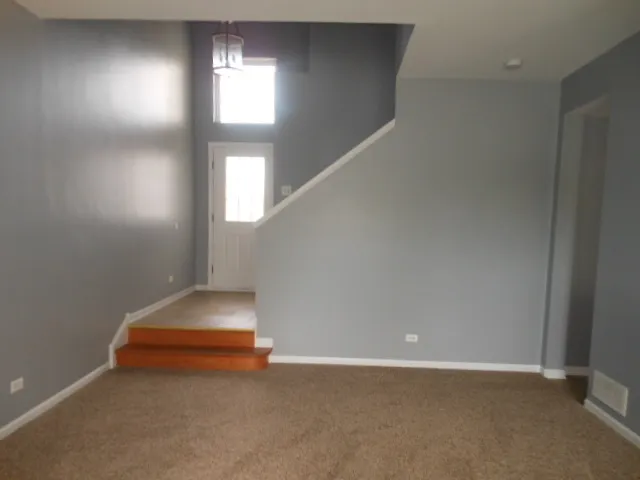 an empty room with stairs and windows