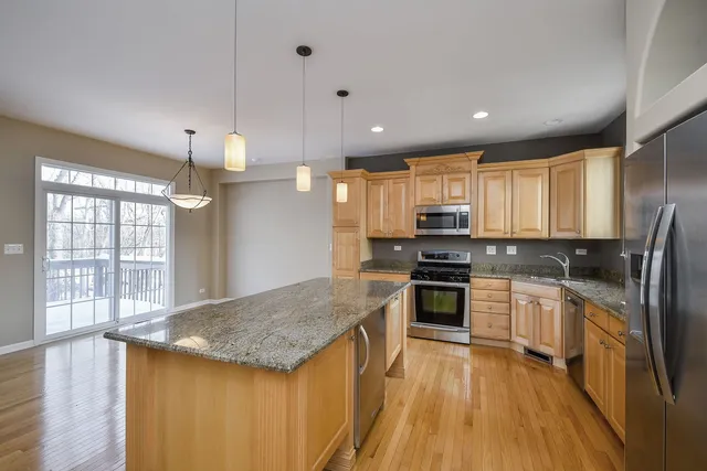 a kitchen with stainless steel appliances granite countertop hardwood floor sink stove and wooden cabinets