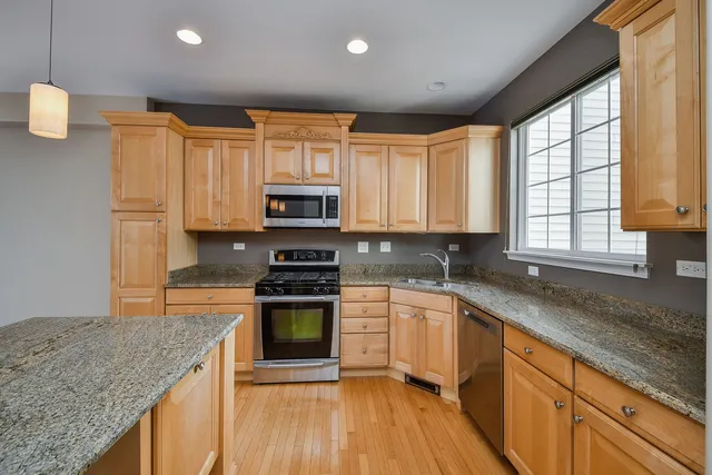 a kitchen with stainless steel appliances granite countertop a stove a sink and a microwave