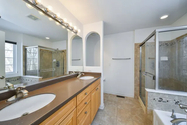 a bathroom with a granite countertop double vanity sink and a mirror