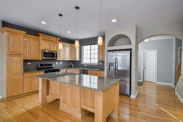 a kitchen with stainless steel appliances granite countertop a refrigerator a stove top oven and a sink