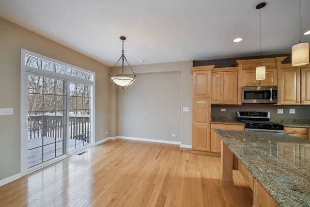 a kitchen with stainless steel appliances granite countertop a refrigerator a stove top oven a sink with wooden floors and cabinets