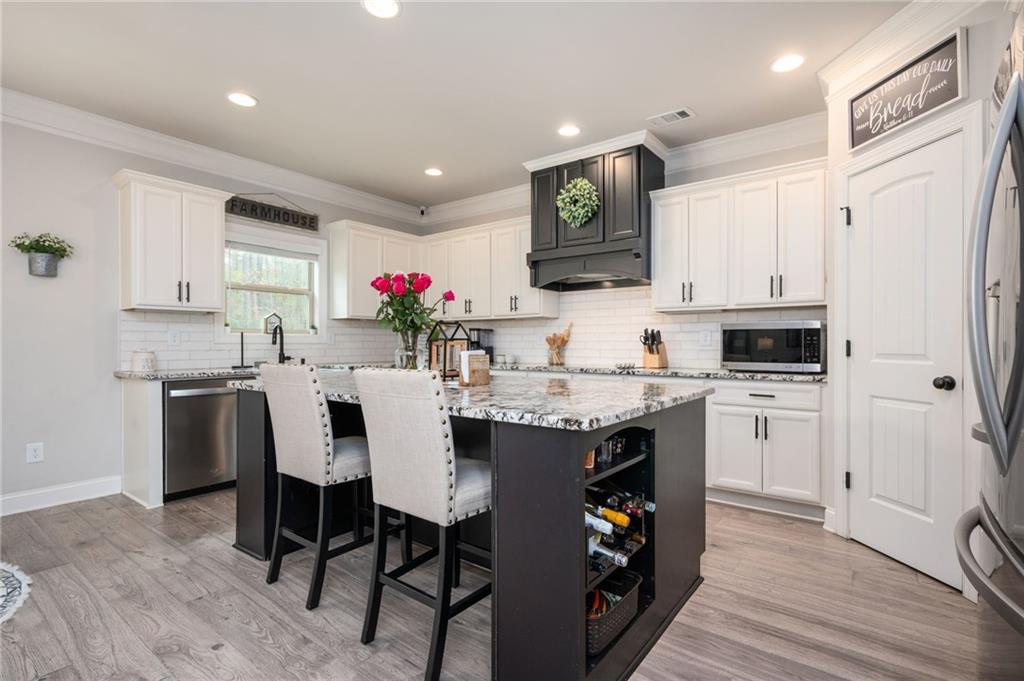 4575 Birch Way Loganville, GA 30052 - Photo 13 of 40 a kitchen with kitchen island granite countertop a sink and white cabinets