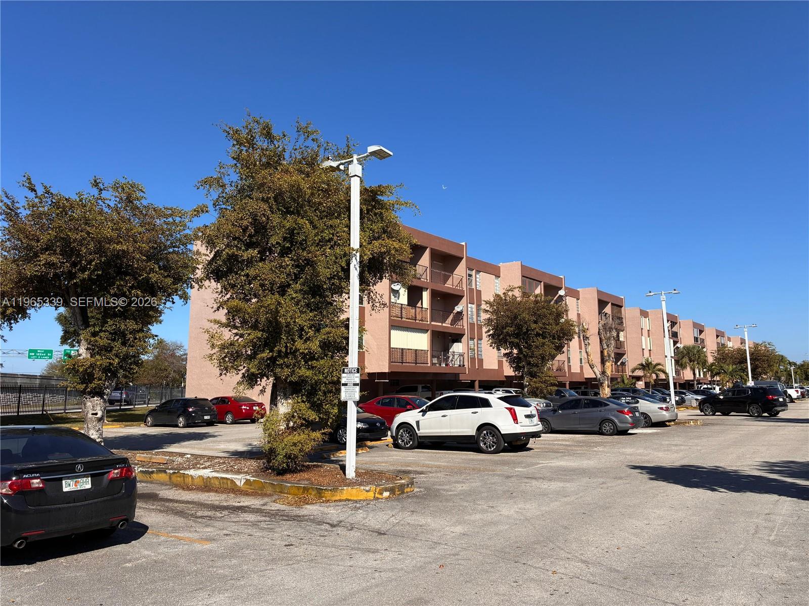 1900 West 68th Street, Unit G103 Hialeah, FL 33014 - Photo 16 of 20 a view of road with card parked on side and retail shops