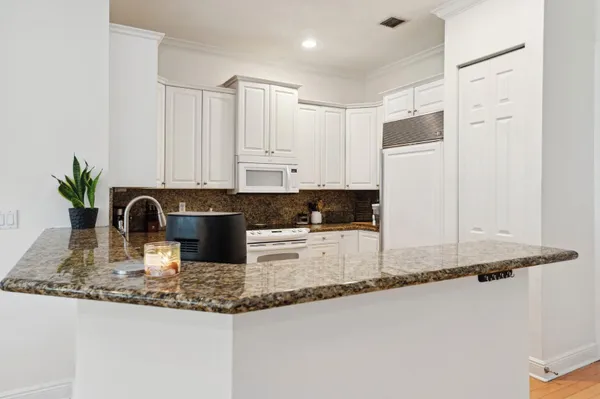 a kitchen with granite countertop a sink a stove and white cabinets