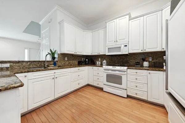 a white kitchen with granite top and stainless steel appliances