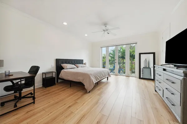 a spacious bedroom with a bed and flat tv screen on the dresser