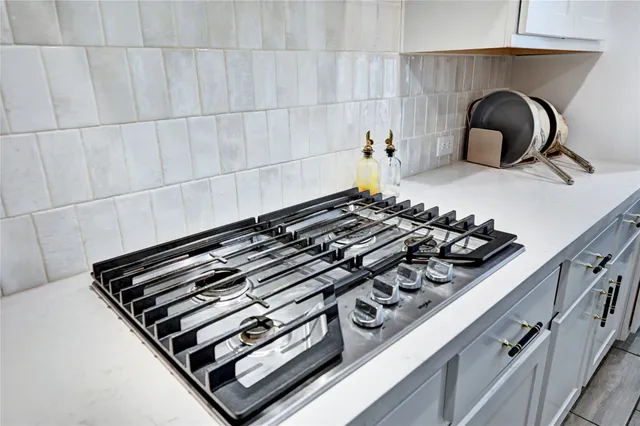 a kitchen with stainless steel appliances white cabinets and a stove top oven