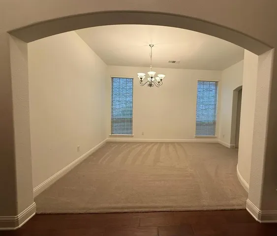an empty room with a chandelier fan and wooden floor