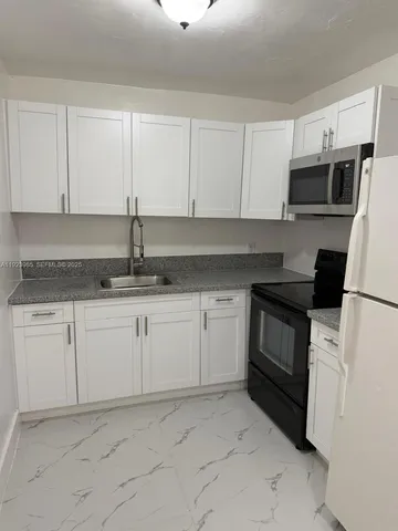 a kitchen with granite countertop white cabinets white stainless steel appliances and sink