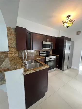 a kitchen with stainless steel appliances granite countertop a sink a stove a refrigerator a washer dryer and a dining table