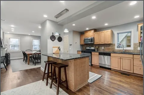a kitchen with stainless steel appliances granite countertop wooden cabinets a dining table and chairs
