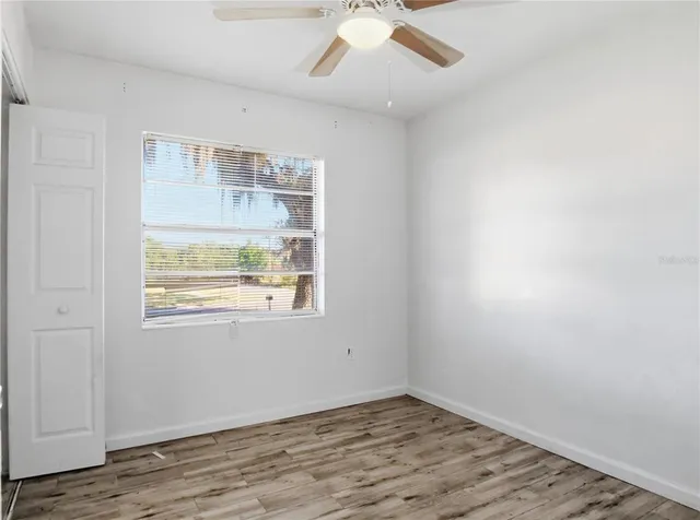a view of empty room with wooden floor and fan