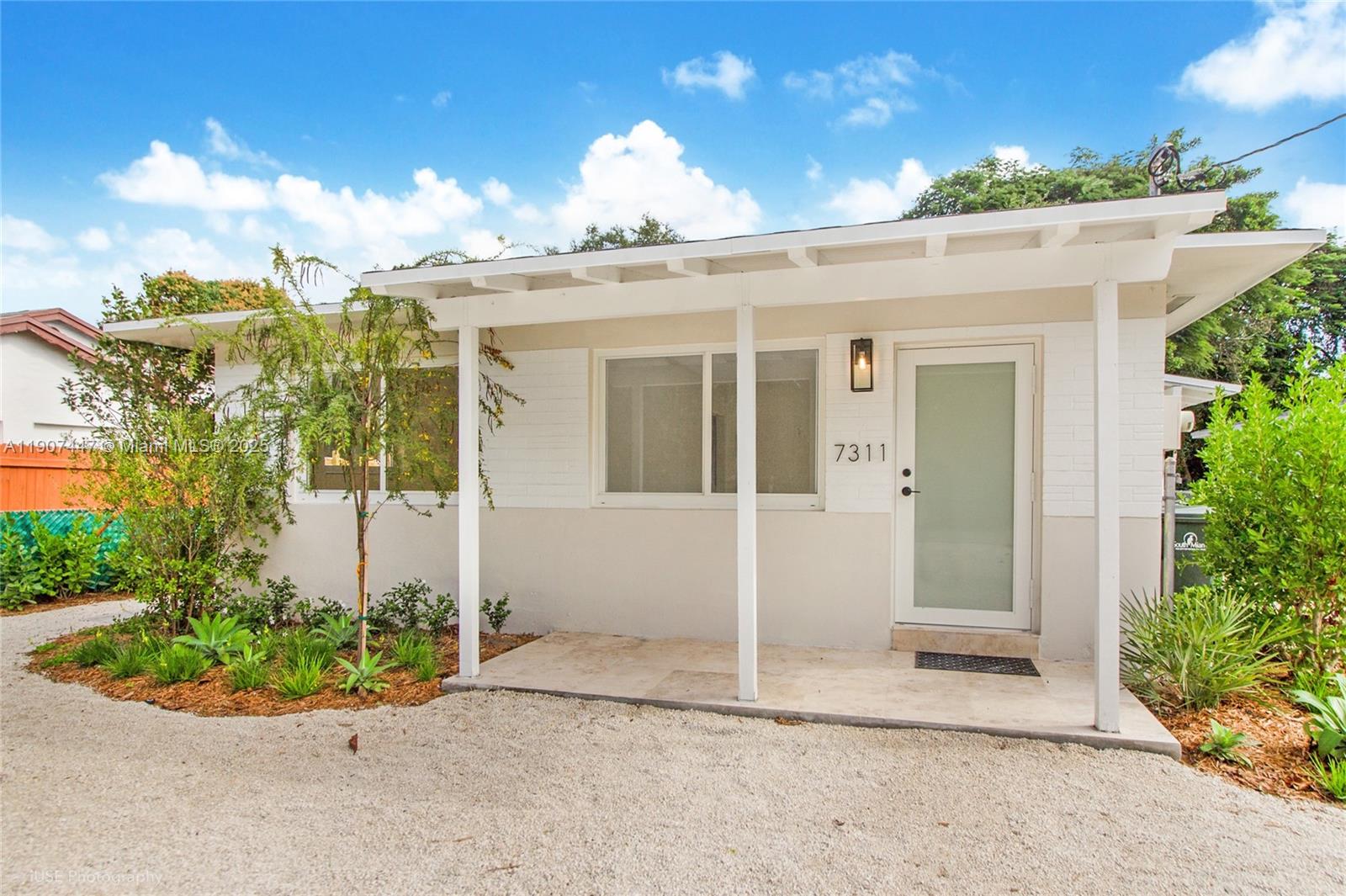 7311 Southwest 63rd Court, Unit 1 South Miami, FL 33143 - Photo 1 of 14 a view of a white house with a large windows and plants